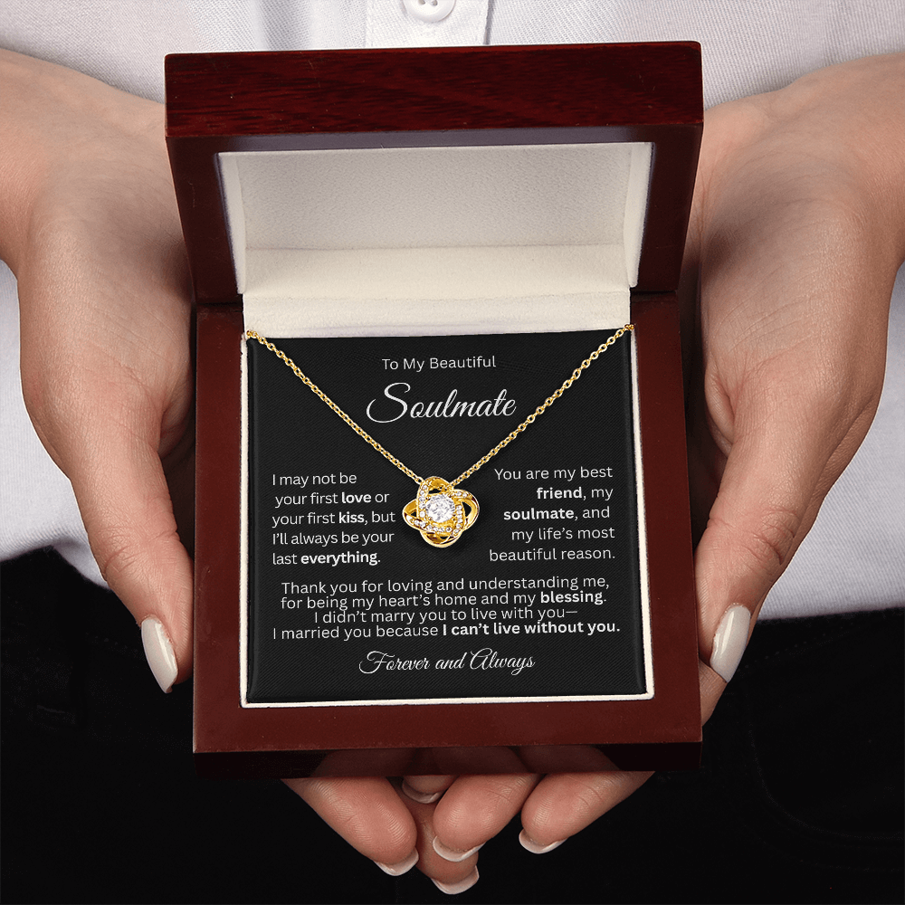 Gold love knot necklace in a red gift box with a heartfelt “To My Beautiful Soulmate” message card, held in a woman's hand.