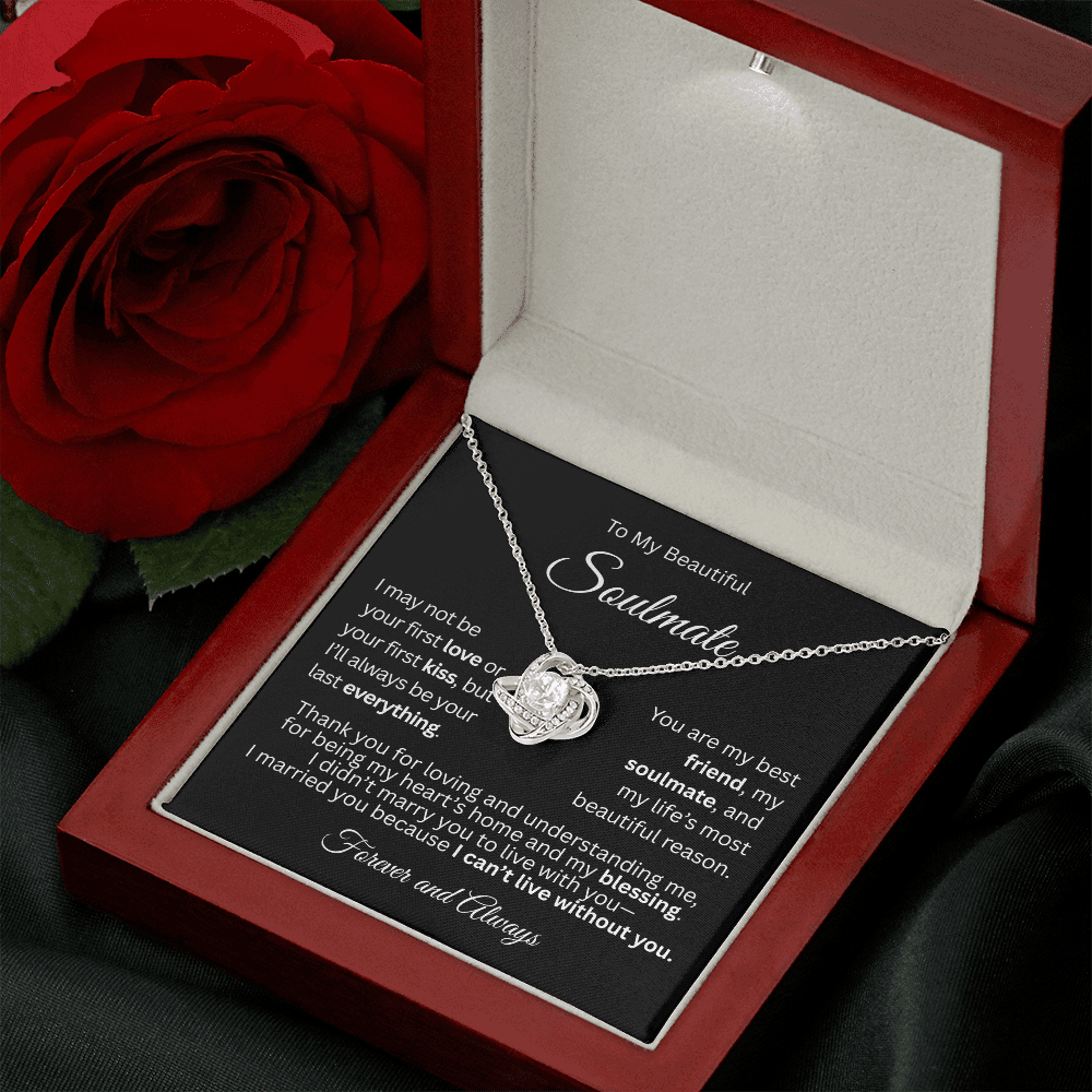 White gold love knot necklace in a mahogany gift box with a heartfelt “To My Beautiful Soulmate” message card, rose on table.