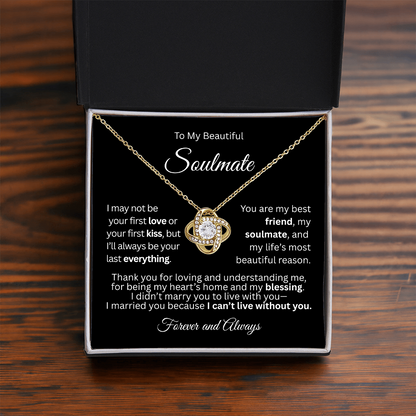 Gold love knot necklace in a red gift box with a heartfelt “To My Beautiful Soulmate” message card, on a brown table.
