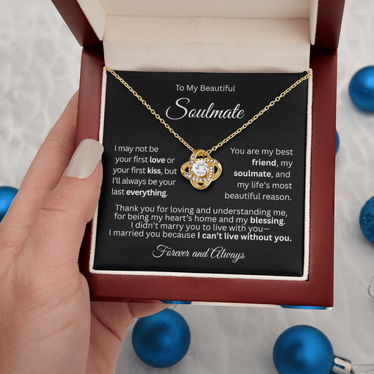 Gold love knot necklace in a red gift box with a heartfelt “To My Beautiful Soulmate” message card, held in a woman's hand.